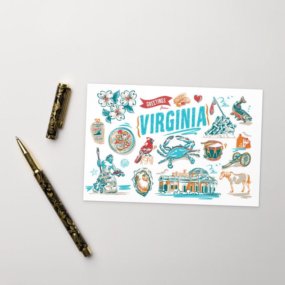 A white greeting card featuring colorful hand-drawn illustrations of Virginia landmarks, symbols, and the word 'VIRGINIA' in large blue letters, styled on a light gray surface with a gold-patterned pen and pen cap beside it.