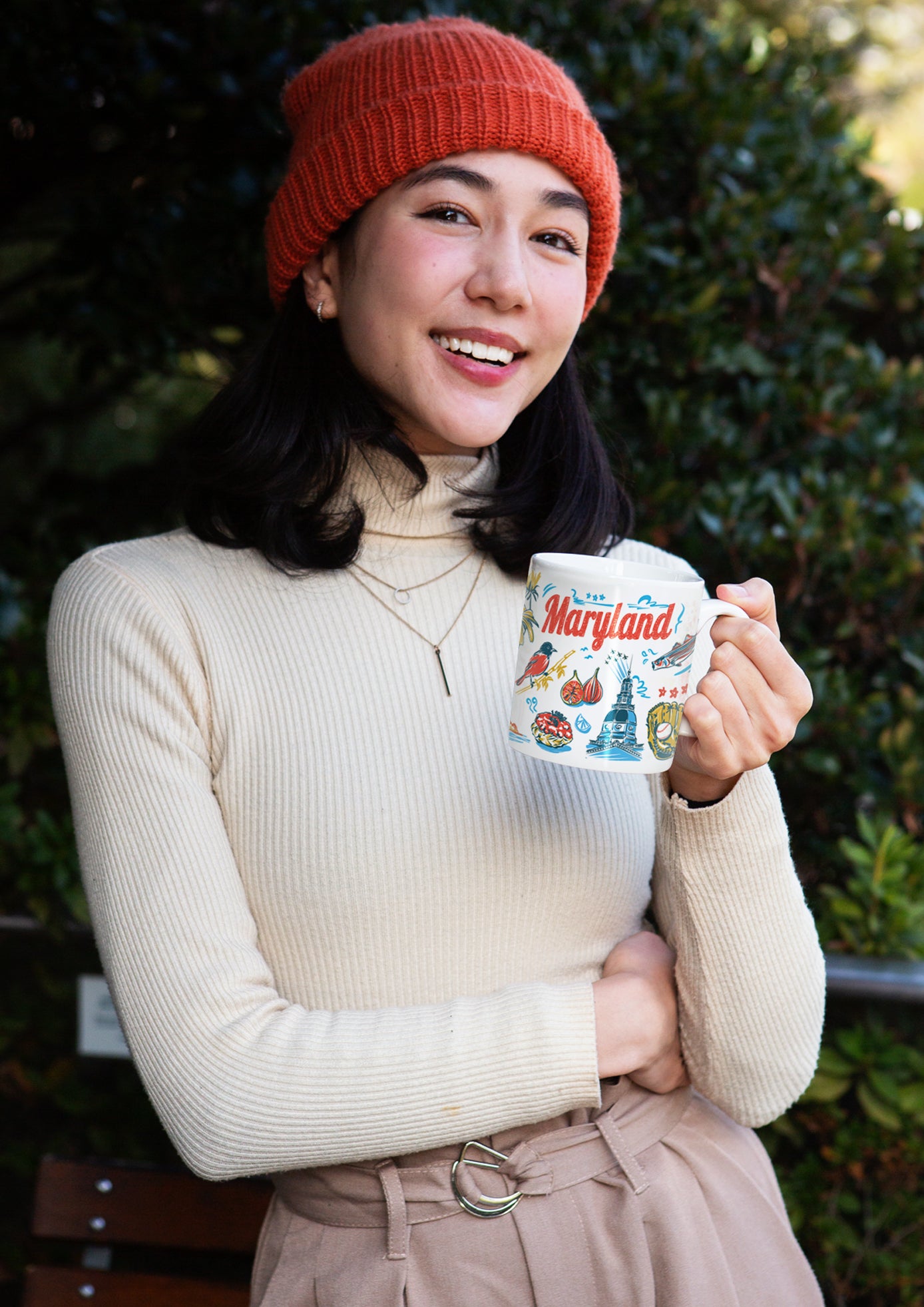 Woman holding a mug with a scenic design outdoors