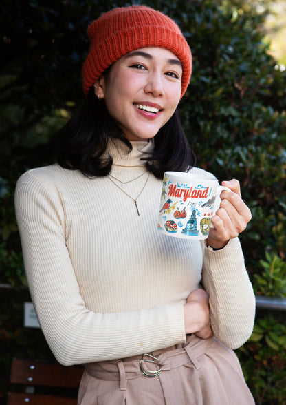 Woman holding a mug with a scenic design outdoors