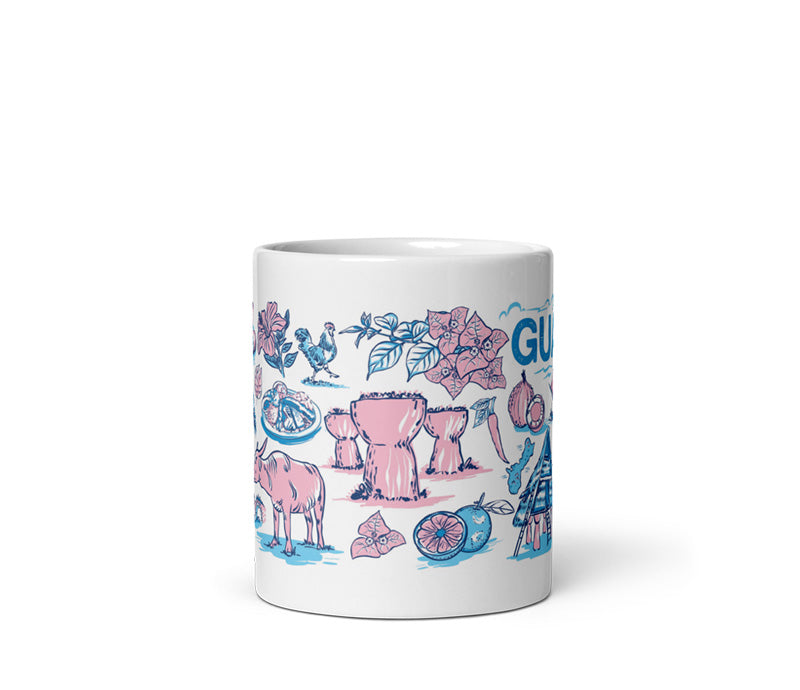 A white ceramic mug featuring a colorful hand-drawn illustration of Guatemalan culture, including a pink iguana, blue toucan, pink flowers, and the word 'GUATEMALA' on a clean white background.