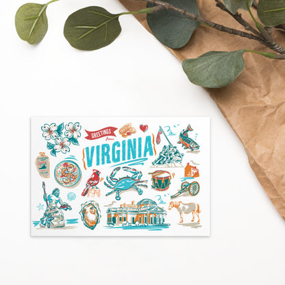 A rectangular printed card featuring colorful illustrated landmarks and symbols of Virginia, styled on a white surface with brown paper and green leaves in the corner.