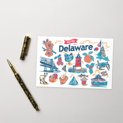 A flat-lay photograph of a 'Greetings from Delaware' art print card, styled with a gold-patterned pen and pen cap on a light gray background.